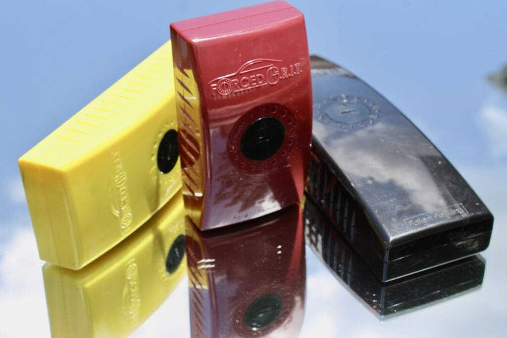 Three colorful vape devices in yellow, red, and black on a reflective surface.
