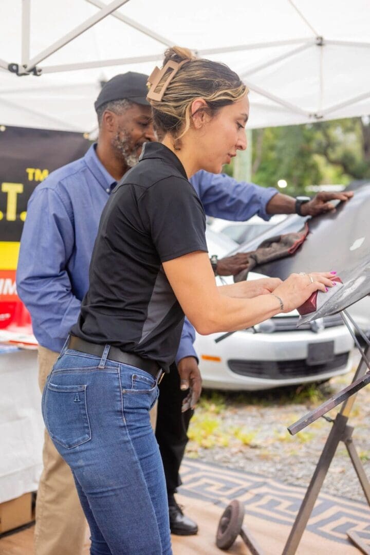 Two people using grills outdoors at a food event.