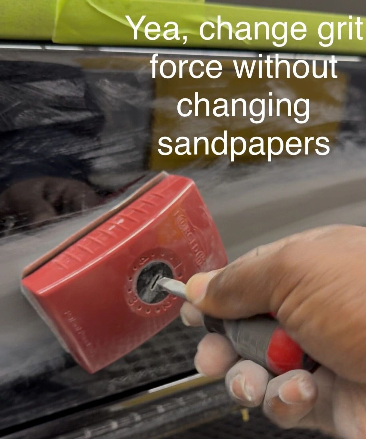 Hand using a sanding block on a surface labeled about changing sandpapers.